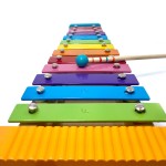 Svoora Ξύλινο Χρωματιστό Μεταλλόφωνο με 12 Νότες, ηχείο, ξύστρα, αναλόγιο και παρτιτούρες παιδικών τραγουδιών.